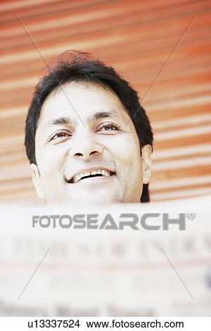 Low angle view of a young man holding a newspaper View Large Photo Image Picture - Low angle view of a young man holding a newspaper. Fotosearch