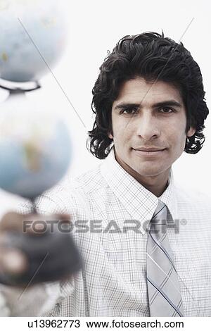 Stock Image - Portrait of a businessman holding a globe. Fotosearch