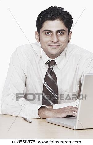 Portrait of a Businessman sitting in front of a laptop View Large Photo Image Stock Photo - Portrait of a Businessman sitting in front of a laptop. Fotosearch