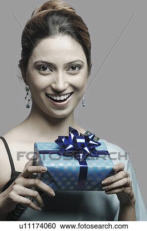 Stock Image - Portrait of a young woman holding a gift. Fotosearch