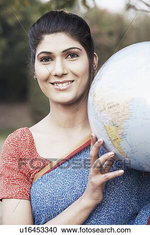 Stock Image - Portrait of a young woman holding a globe. Fotosearch