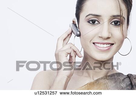 Stock Photo - Portrait of a young woman wearing a hands free device. Fotosearch