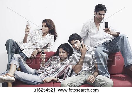 Stock Image - Close-up of two young couples holding mobile phones. Fotosearch