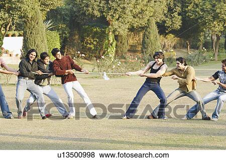 Stock Photo - Group of young men playing tug-of-war. Fotosearch