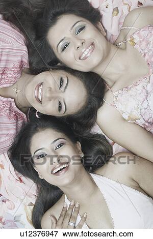 Stock Photo - High angle view of three young women smiling. Fotosearch