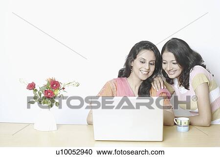 Mid adult woman using a laptop with a young woman beside her View Large Photo Image Stock Image - Mid adult woman using a laptop with a young woman beside her. Fotosearch
