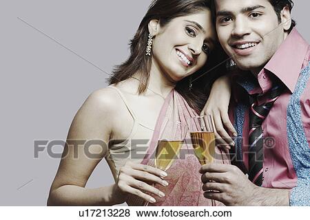 Stock Photo - Portrait of a young couple holding champagne flutes. Fotosearch