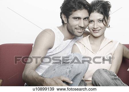 Portrait of a young couple sitting on a couch smiling View Large Photo Image Stock Photo - Portrait of a young couple sitting on a couch smiling. Fotosearch