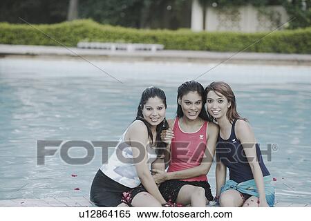 Portrait of three young women sitting on the edge of a swimming pool View Large Photo Image Stock Photography - Portrait of three young women sitting on the edge of a swimming pool. Fotosearch