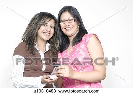 Stock Image - Portrait of two young women holding mobile phones. Fotosearch