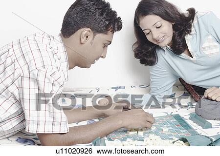 Stock Photograph - Side profile of a young couple playing scrabble. Fotosearch