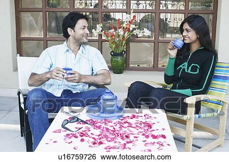 Stock Photograph - Young couple holding cups and smiling. Fotosearch