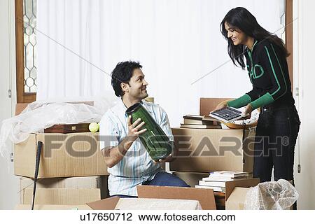 Stock Image - Young man showing a vase to a young woman. Fotosearch
