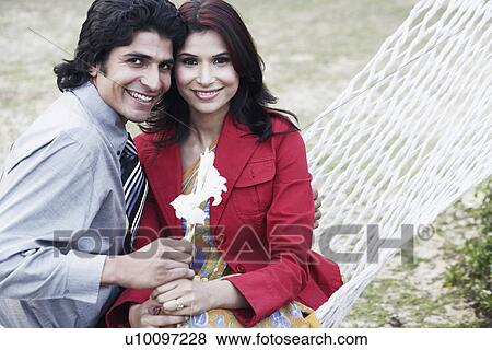 Stock Photo - Close-up of a young couple sitting in a hammock. Fotosearch