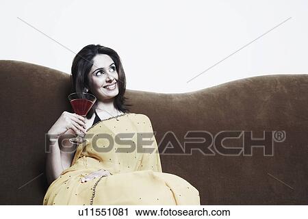 Stock Image - Close-up of a young woman holding a martini glass. Fotosearch