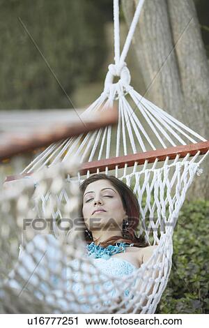 Stock Image - High angle view of a young woman lying in a hammock. Fotosearch