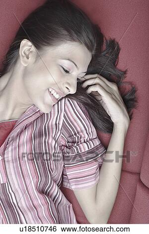 Stock Photograph - High angle view of a young woman lying on a couch. Fotosearch