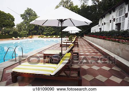 Stock Image - Lounge chairs at the poolside. Fotosearch