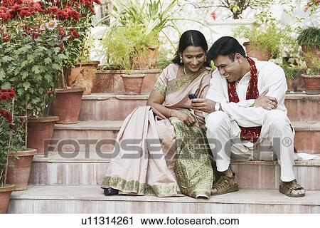 Mid adult couple looking at a mobile phone View Large Photo Image Stock Image - Mid adult couple looking at a mobile phone. Fotosearch