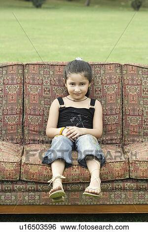 Stock Photograph - Portrait of a girl sitting on a couch outdoors. Fotosearch