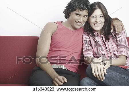 Portrait of a young couple sitting on a couch smiling View Large Photo Image Stock Image - Portrait of a young couple sitting on a couch smiling. Fotosearch