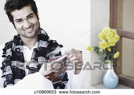 Stock Image - Portrait of a young man holding a magazine. Fotosearch