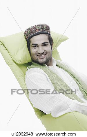 Stock Photo - Portrait of a young man sitting on a chair. Fotosearch
