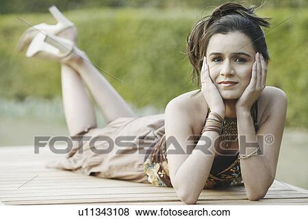 Stock Photo - Portrait of a young woman lying on a bench. Fotosearch