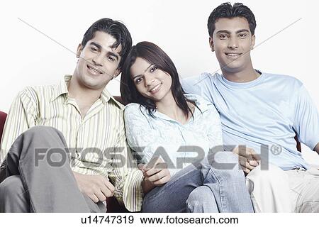 Portrait of a young woman sitting on a couch with two young men View Large Photo Image Stock Photo - Portrait of a young woman sitting on a couch with two young men. Fotosearch