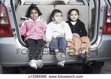 Stock Photograph - Portrait of three sisters sitting in the back of a car. Fotosearch