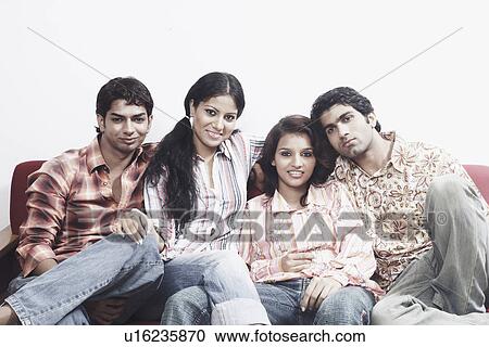 Stock Image - Portrait of two young couples sitting together on a couch. Fotosearch