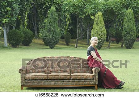 Stock Photograph - Side profile of a mature woman sitting on a couch outdoors. Fotosearch