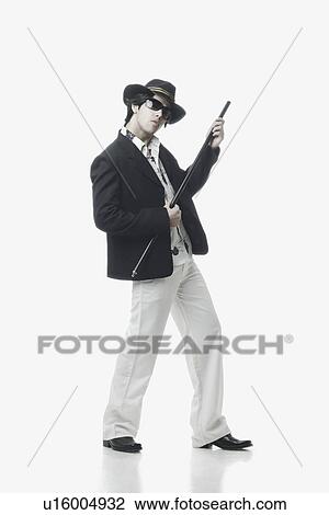 Stock Image - Side profile of a young man holding a cane. Fotosearch