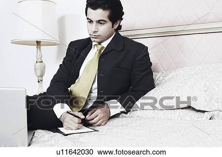 Stock Image - Businessman sitting on the bed. Fotosearch