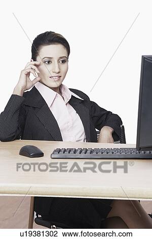 Businesswoman sitting in front of a computer View Large Photo Image Stock Image - Businesswoman sitting in front of a computer. Fotosearch
