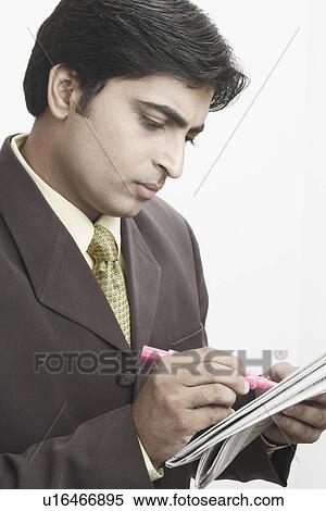 Close-up of a businessman writing on a newspaper View Large Photo Image Stock Photography - Close-up of a businessman writing on a newspaper. Fotosearch