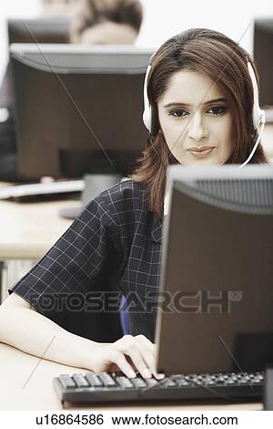 Stock Photograph - Close-up of a businesswoman wearing a headset sitting in front of a computer. Fotosearch