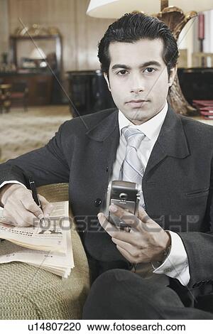 Portrait of a businessman holding a mobile phone View Large Photo Image Stock Image - Portrait of a businessman holding a mobile phone. Fotosearch