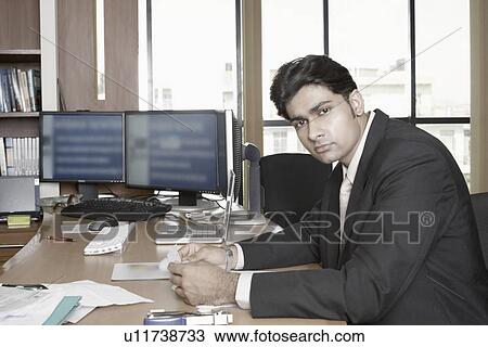Stock Image - Portrait of a businessman sitting in an office. Fotosearch
