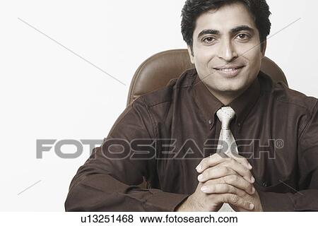 Portrait of a businessman sitting with his hands clasped View Large Photo Image Stock Photo - Portrait of a businessman sitting with his hands clasped. Fotosearch