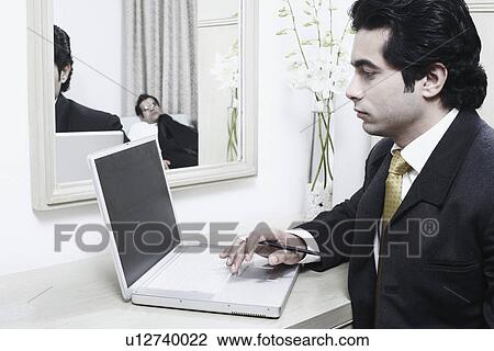 Side profile of a businessman using a laptop in front of a mirror View Large Photo Image Stock Image - Side profile of a businessman using a laptop in front of a mirror. Fotosearch