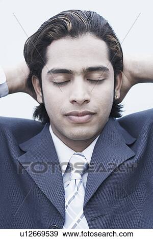 Close-up of a businessman relaxing with his hands behind his head View Large Photo Image Stock Photo - Close-up of a businessman relaxing with his hands behind his head. Fotosearch