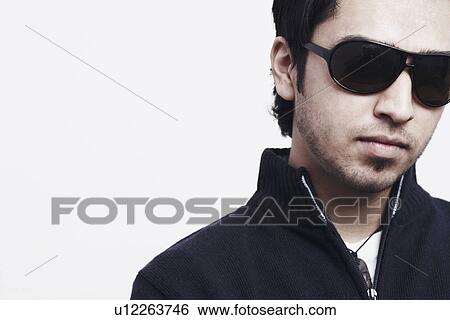 Close-up of a young man wearing sunglasses View Large Photo Image Stock Photograph - Close-up of a young man wearing sunglasses. Fotosearch