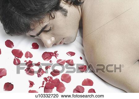 Stock Image - High angle view of a young man lying on a massage table. Fotosearch