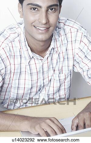 Stock Image - High angle view of a young man working on a laptop. Fotosearch