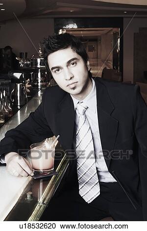 Portrait of a businessman sitting at a bar counter with a cocktail View Large Photo Image Stock Image - Portrait of a businessman sitting at a bar counter with a cocktail. Fotosearch