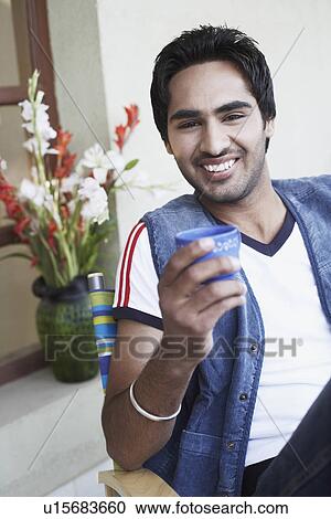 Stock Image - Portrait of a young man holding a cup. Fotosearch