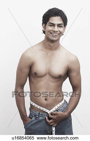 Portrait of a young man measuring his waist with a measuring tape View Large Photo Image Stock Photography - Portrait of a young man measuring his waist with a measuring tape. Fotosearch