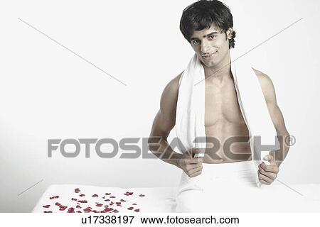 Stock Photo - Portrait of a young man sitting on a massage table. Fotosearch