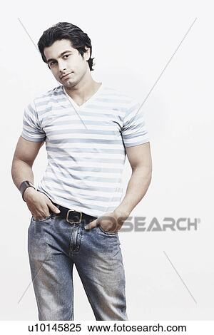 Portrait of a young man standing with his hands in his pockets View Large Photo Image Stock Photography - Portrait of a young man standing with his hands in his pockets. Fotosearch